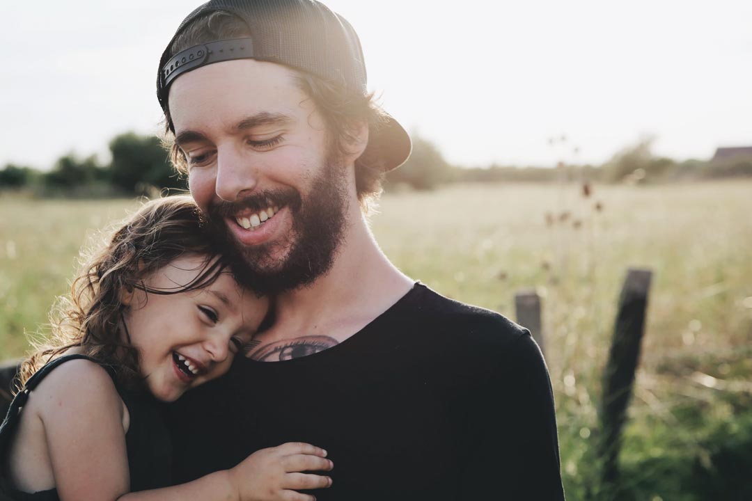 Vater hält lachend seine Tochter im Arm
